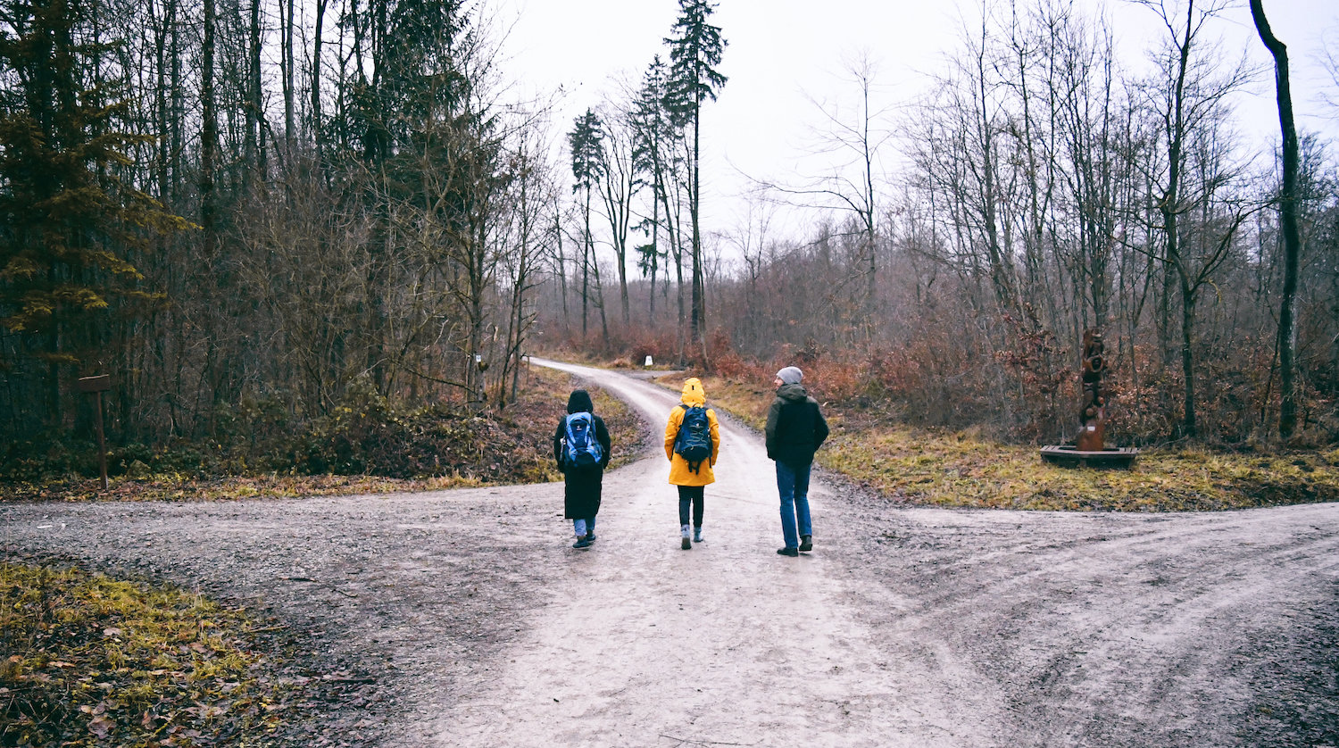 Drei Menschen wandern über eine Wegkreuzung